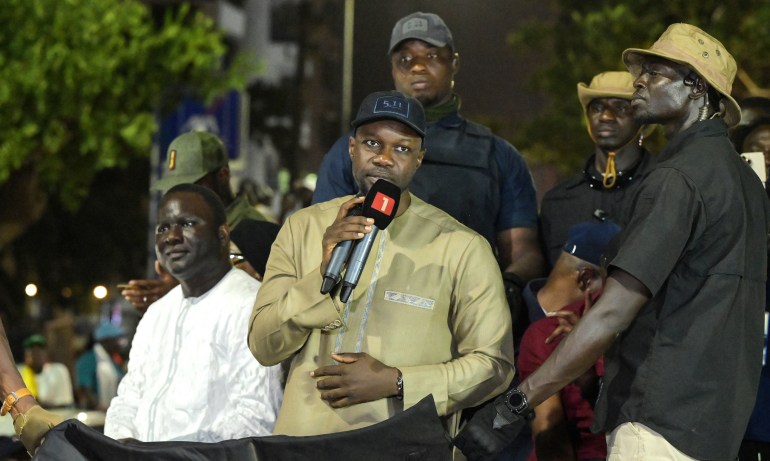 Senegal's Prime Minister and Pastef party leader Ousmane Sonko (C) addresses a speech flanked by security as he takes part in a caravan as part of an electoral campaign for early elections following the dissolution of the National Assembly in Dakar on November 12, 2024. - Senegalese Prime Minister Ousmane Sonko urged his supporters to remain calm on November 12, 2024, after calling on them to take revenge for the violence he claimed had been committed against his activists by opponents, who denounced it as a call to murder six days ahead of parliamentary elections due to elect a new parliament on November 17, 2024 after Senegal's President dissolved the opposition-dominated chamber in September. (Photo by SEYLLOU / AFP)