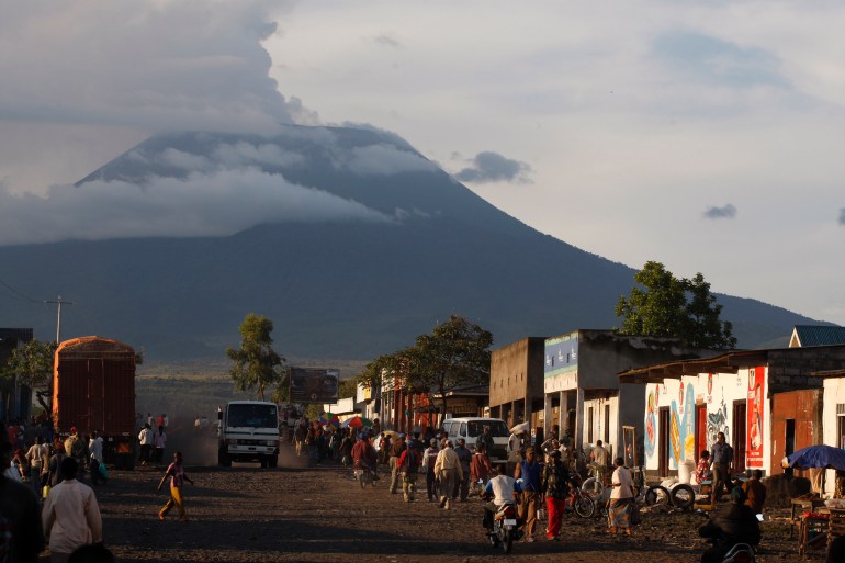 In this March 29, 2010 photo, residents walk along a neighborhood street in Goma, Congo, against the backdrop of Mount Nyiragongo, one of Africa's most active volcanos. Mount Nyiragongo is the ultimate symbol of death in Goma, the lakeside city it shadows and has overrun several times. Yet it's also a symbol of rebirth and resilience for a nation slowly emerging from war. In March, park rangers cleared Rwandan militias from its slopes and reopened the summit for the first time in a year and a half. (AP Photo/Rebecca Blackwell)