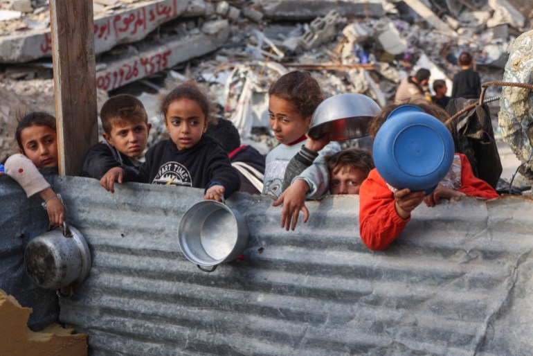 Displaced Palestinian children queue to get a portion of cooked food from a charity kitchen in Beit Lahia in the northern Gaza Strip, ahead of the iftar fast-breaking meal during the Muslim holy month of Ramadan on March 9, 2025. Israel's energy minister said on March 9 he had given instructions to stop supplying electricity to Gaza, a week after Israel blocked all aid into the war-ravaged Palestinian territory. (Photo by Omar AL-QATTAA / AFP)