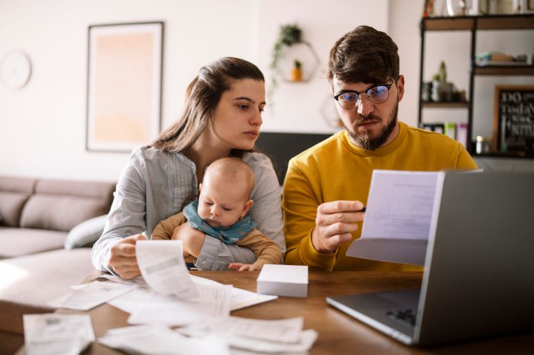 Young family with baby worried about family budget and high taxes and bills. Inflation concept.